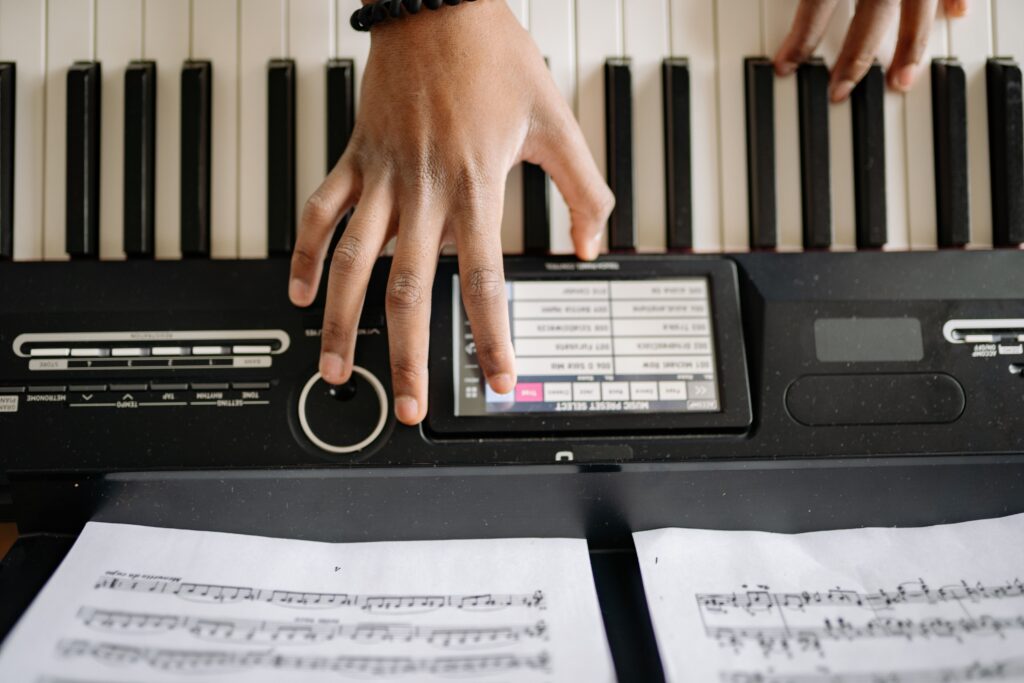 A detailed view of hands playing an electric keyboard with sheet music in the foreground.
